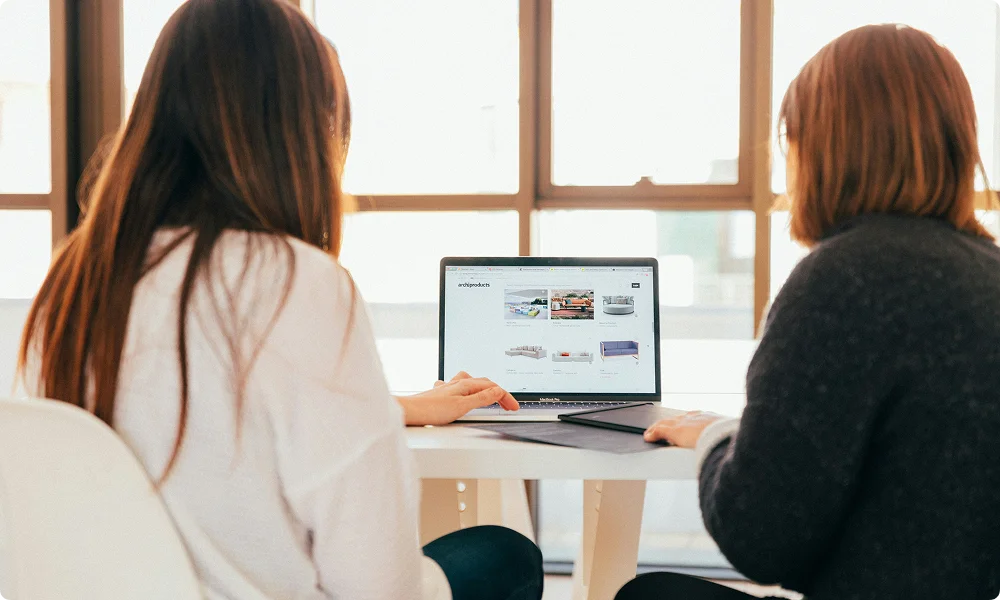 Two employees working together while looking on the laptop